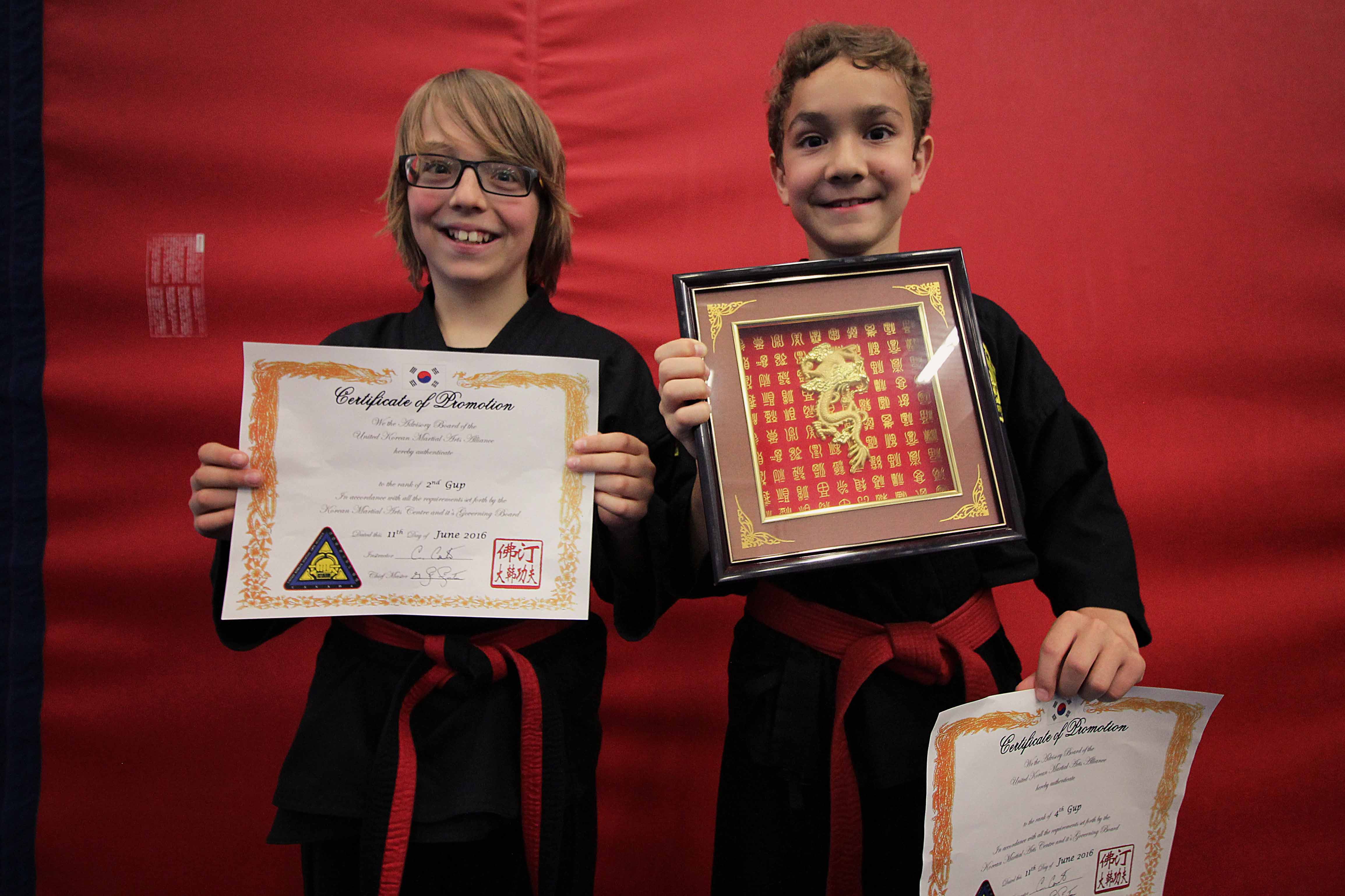 Two Valley KMAC students showing off their tournament awards and promotions.